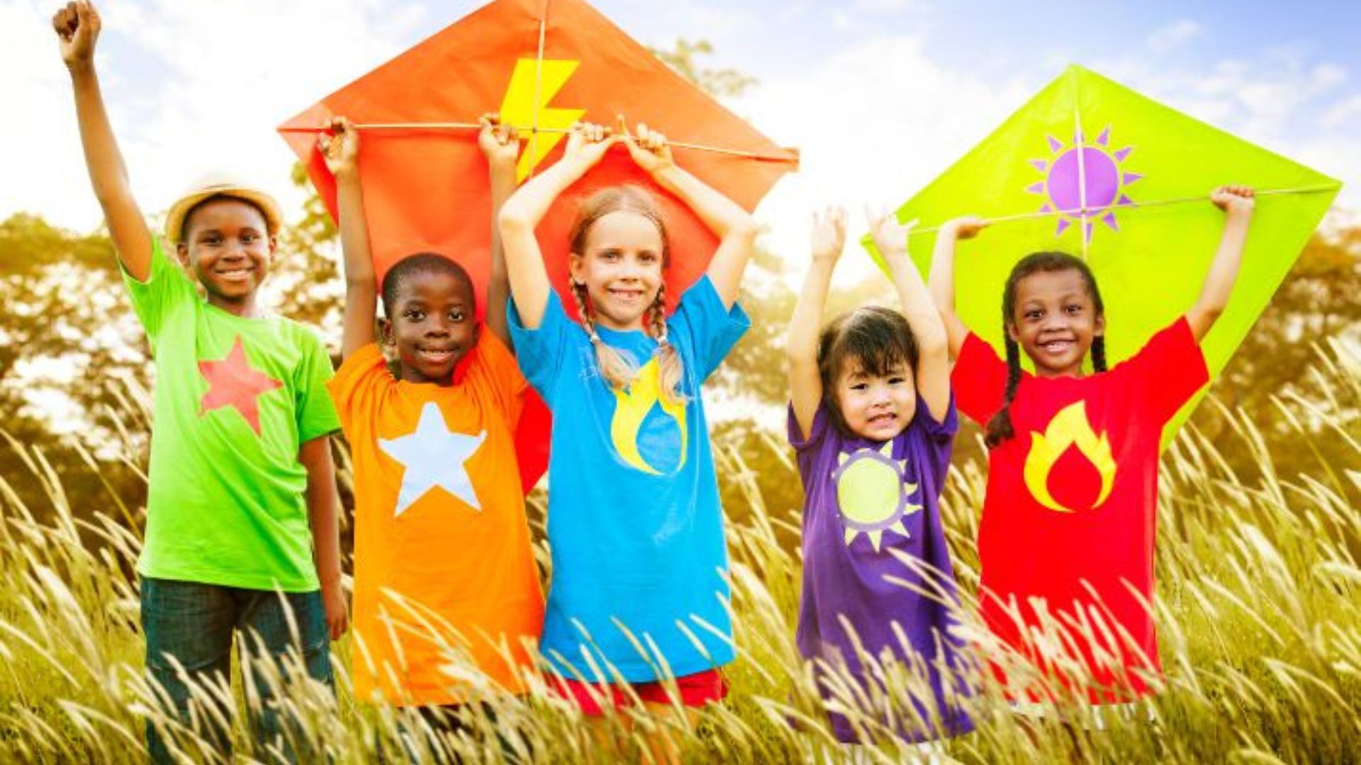a group of children holding colorful kites in a field