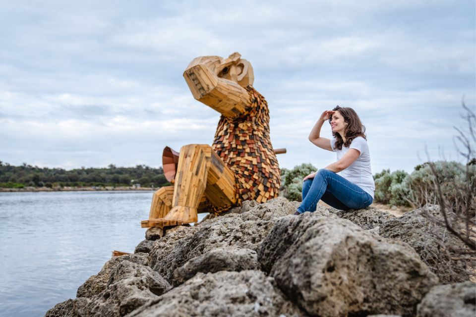 a woman sitting on a rock next to a wooden giant sculpture