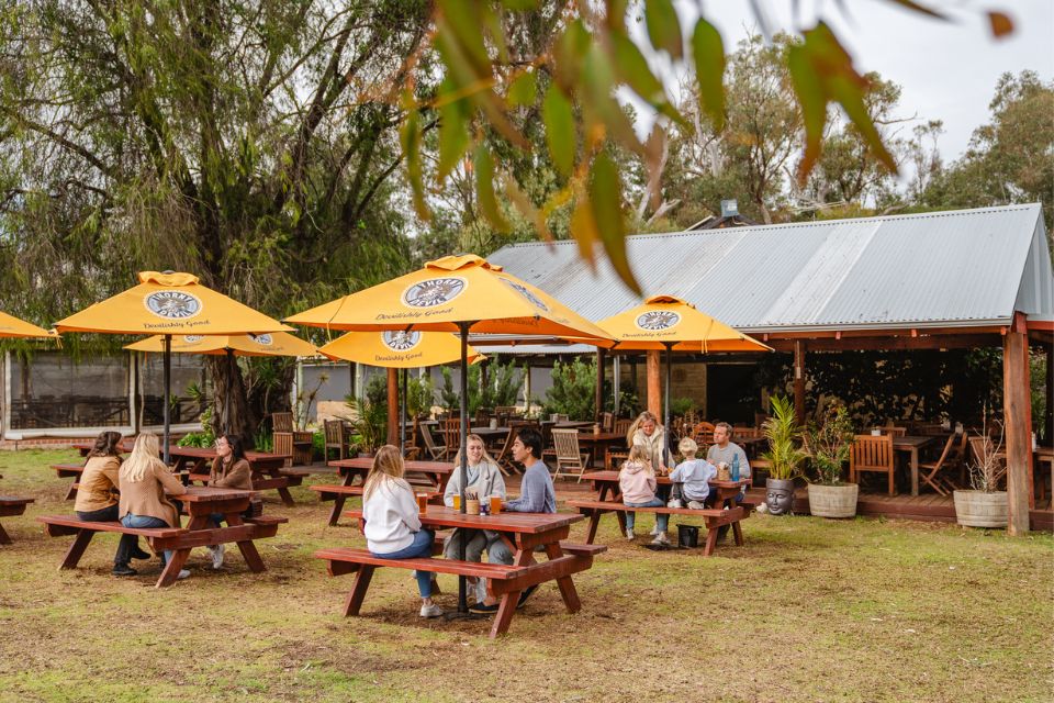 a group of people sitting at picnic tables under yellow umbrellas at a brewery