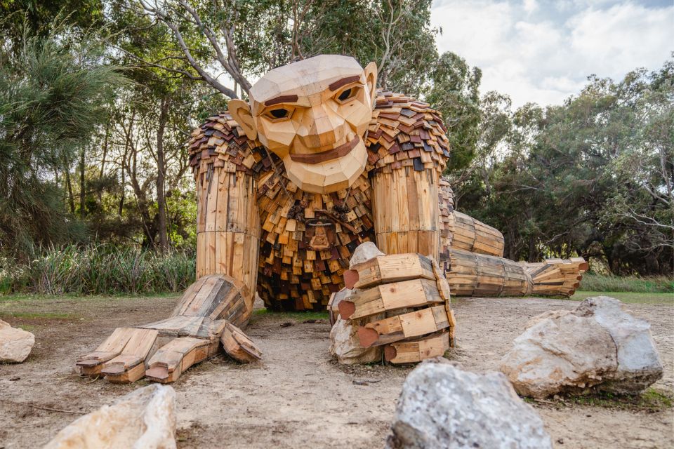 a large wooden sculpture of a person sitting on the ground