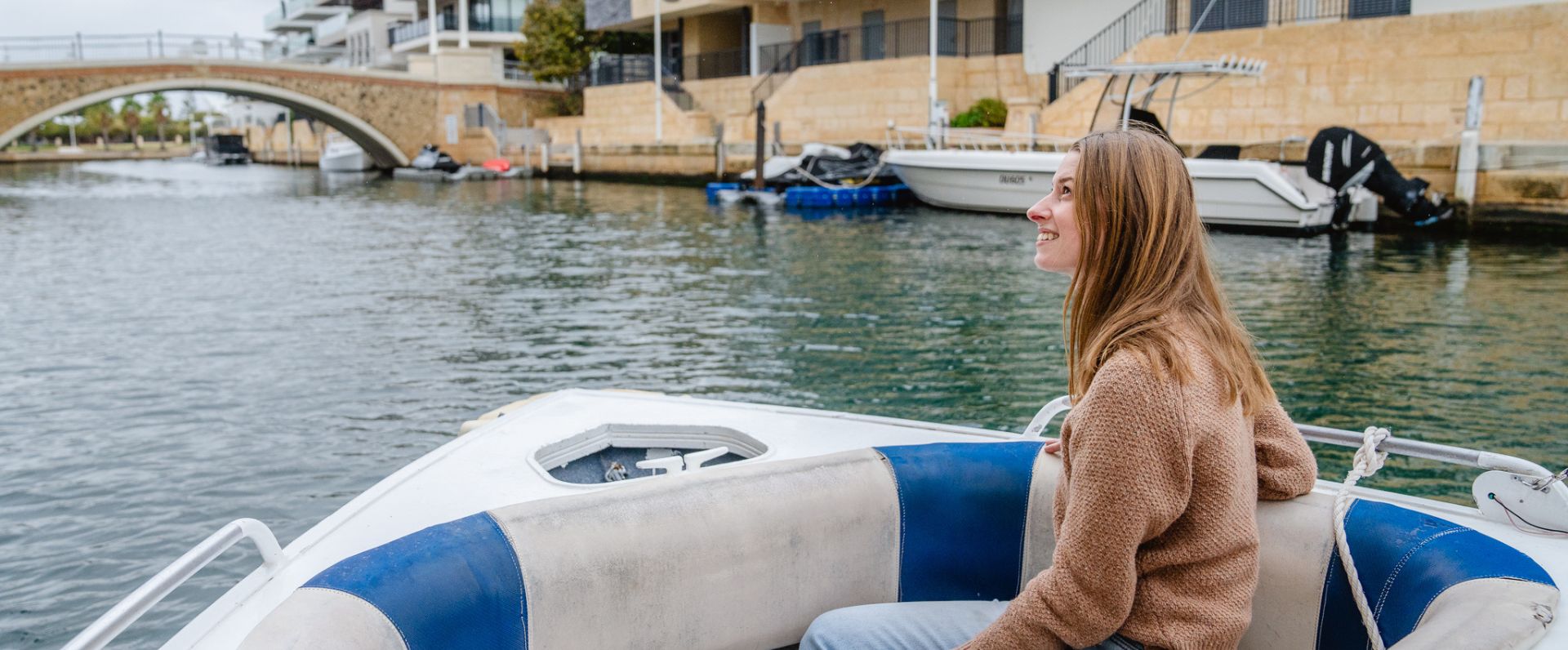 a woman is sitting in the back of a boat on the water