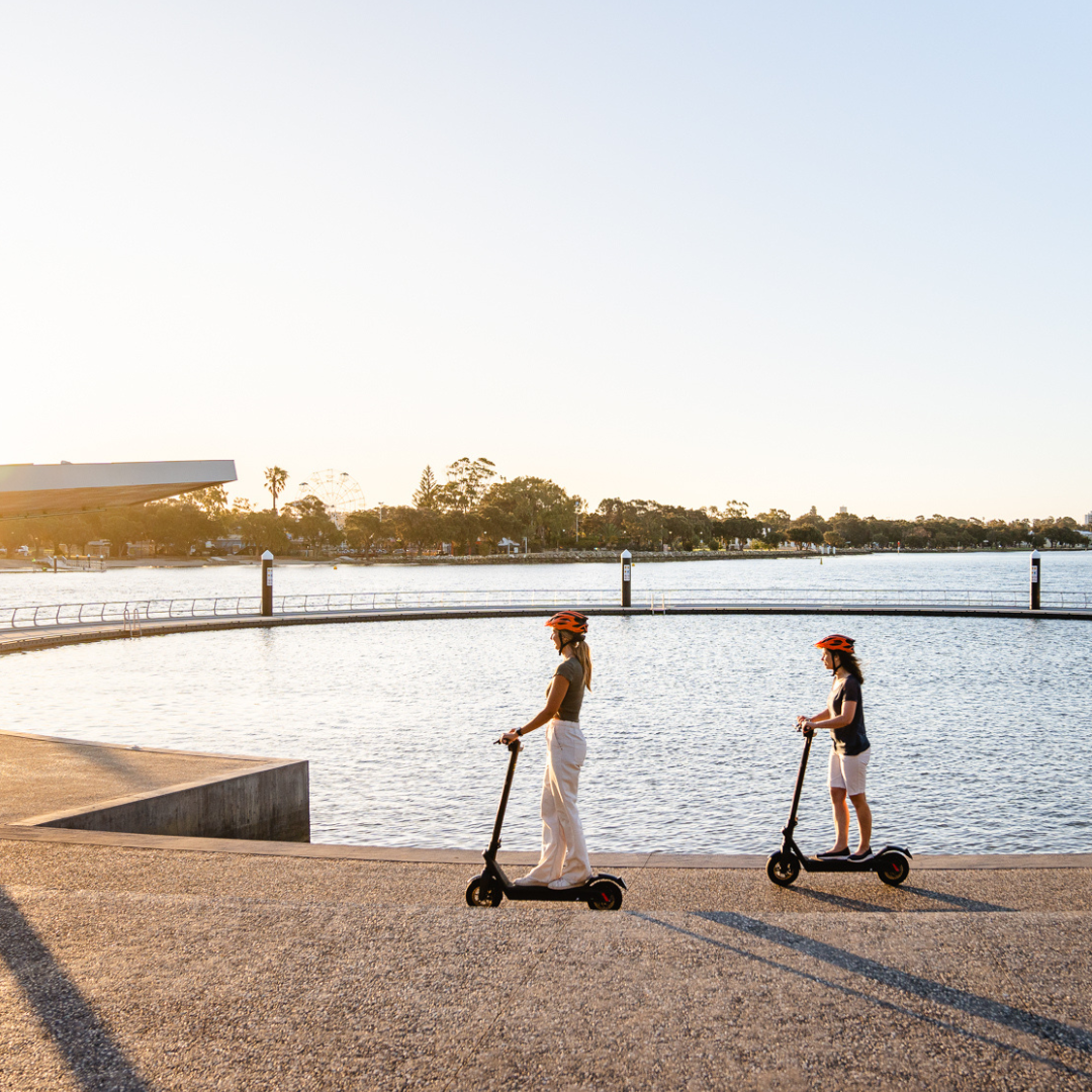 two women riding electric scooters near the Mandurah Estuary Pool