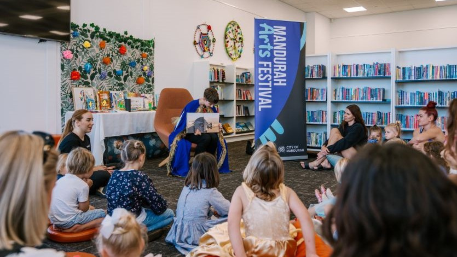 a group of children sitting on the floor in front of a bookshelf