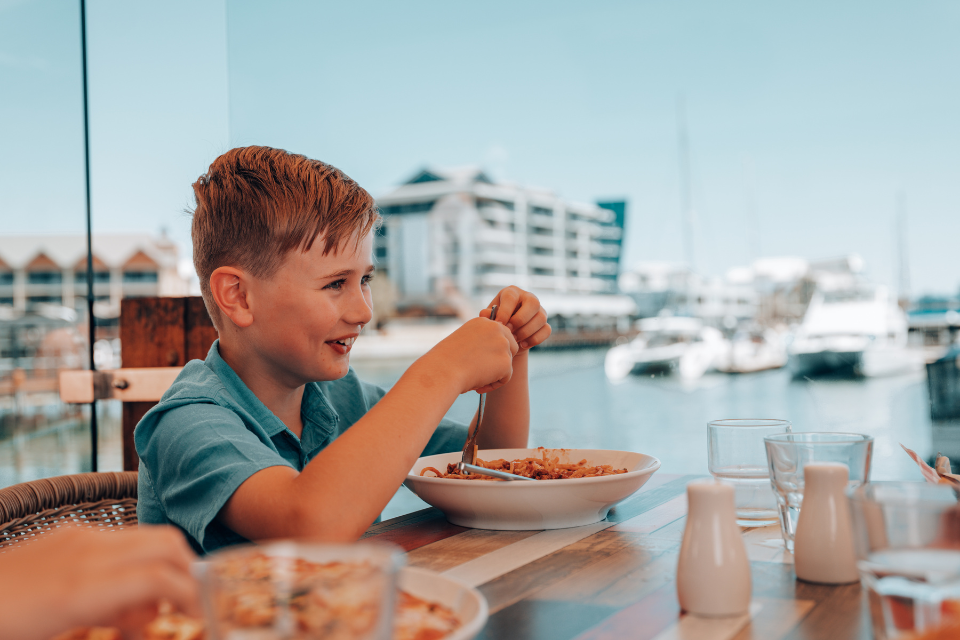 a young boy is eating spaghetti at a restaurant