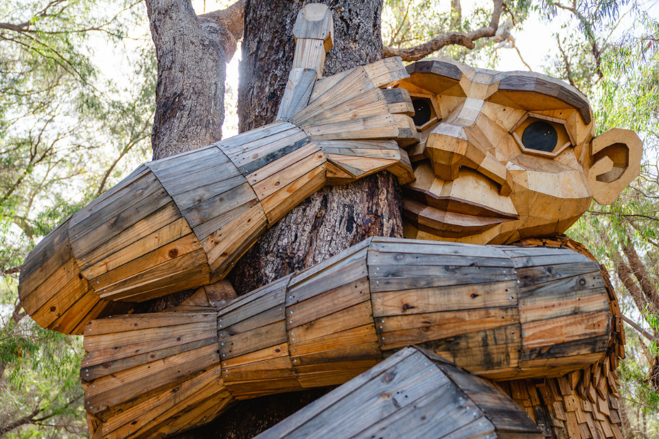 a wooden sculpture of troll hugging a tree