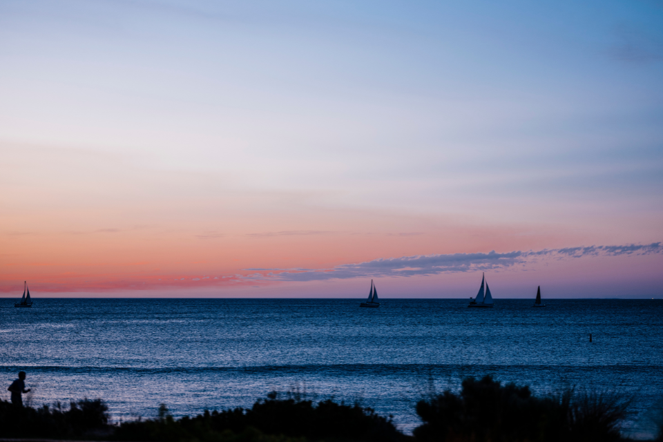 sailboats in the ocean at sunset