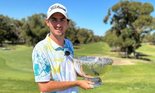 a man holding a trophy on a golf course